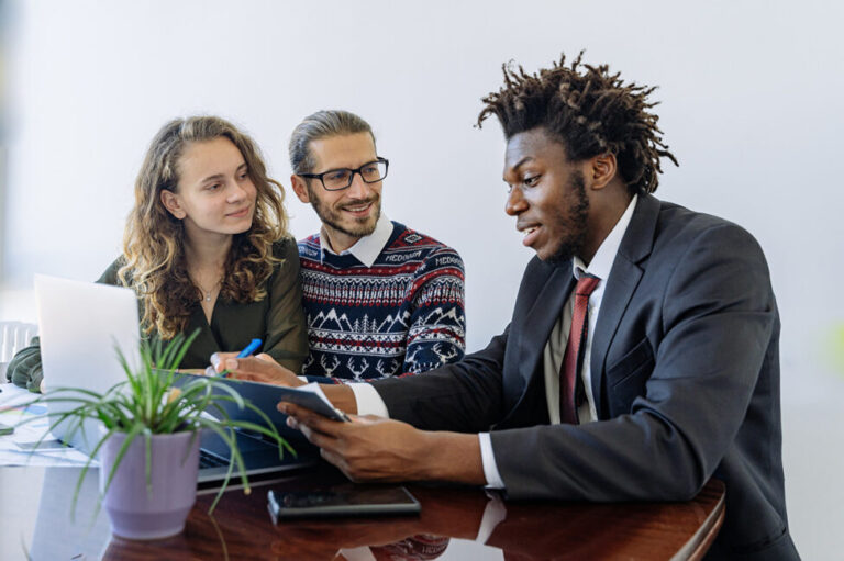 a young couple sits at a desk with a financial advisor